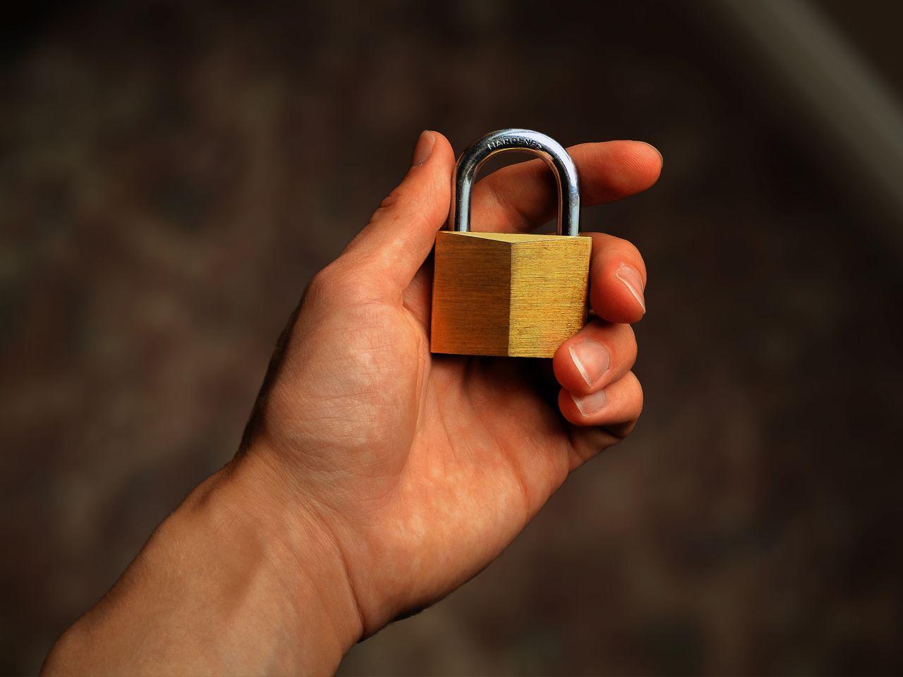 A hand holding a brass padlock