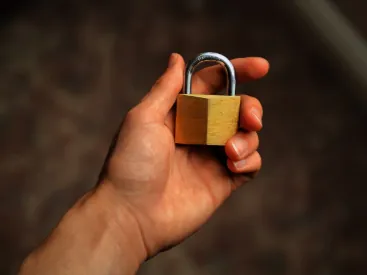 A hand holding a brass padlock